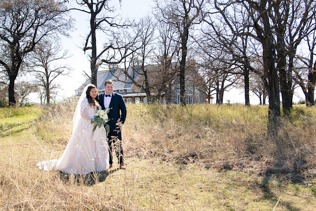 May 1st is a special day in the lives of Jonathan and Katelin, for it was on this day one year ago that he proposed at the Myriad Gardens in Oklahoma City.  Both Katelin and Jonathan grew up in Stillwater, went to the same middle and high school, but didn’t actually get to know each other until one of Katelin’s friends suggested that she invite Jonathan to the Senior Prom.  Katelin didn’t think that was a good idea at all, since she described him as “a very shy, nerdy kid,” and she was a “social butterfly.”  Little did she know that “we would really hit it off…and things have just gotten better every day since!”     And what was not to love about this day?  The bride and groom chose the Sparrow in Stillwater as their venue, with a rustic, architecturally modern barn, and 30 beautiful acres to roam in.   Katelin and her bridesmaids spent the morning, tucked away in their own getting-ready suite, finishing up with hairdresser, make-up artist, and assisting the bride into her gorgeous gown.  They were also trying to be a calming influence, but as the time for the First Look arrived, everyone was excited…and emotional.  Especially the newlyweds-to-be!     Katelin and Jonathan exchanged sweet letters during the First Look, which brought joyful tears to each of them, and then they were whisked off to create some magical couples’ portraits.  Wedding party pictures followed, as the bridesmaids gathered around Katelin, and the groomsmen’s personalities emerged as they enacted the “Mario” jump!    At last the hour came for the ceremony to begin.  The bridesmaids, dressed in pastel shades of pink and lavender, came down the staircase on the hand of their respective groomsman, while Jonathan waited patiently at the altar for his bride.  Added to the wedding party were the couple’s two Golden Retrievers—the “flower girl and ring bearer.”  The bride was stunning in her lace-embroidered, elegant wedding gown, carrying a lush floral bouquet consisting of white roses, white ranunculus, and lush greenery.     After the couple exchanged vows, guests were invited to participate in a buffet dinner while they enjoyed the festivities of the evening…the first dance, dances with the respective parents, toasts to the bride and groom, and dancing.  The culmination of the evening took place when Jonathan, in light-hearted fun, smashed some of the wedding cake on Katelin’s face, only to be sprayed with champagne when the bottle popped off as he was opening it!  True to her humorous good nature, Katelin took it all in stride!     This is one of those weddings we will remember, reminding us that soul mates do find one another in the most wonderful of unexpected ways…and we wish this delightful couple a lifetime of happiness together!