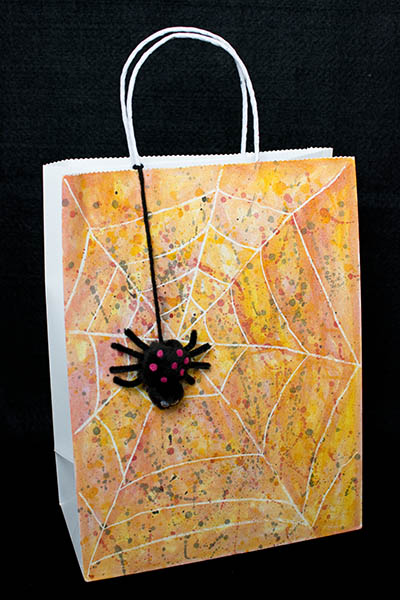 Spider web Trick or treat bag made using a white crayon as a watercolor resist with cute black spider with pink spots