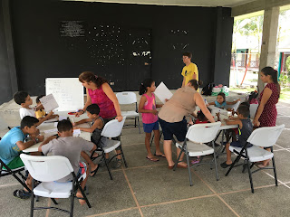 Two tables are set up in the outdoor pavilion. Deanne teaching at one table.