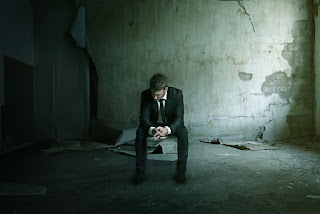 Sad man sitting in a bombed out basement perhaps after a devastating project post mortem