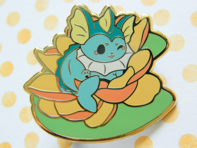 an enamel pin of the pokemon vaporeon sitting on a yellow orange lotus flower and lily pad