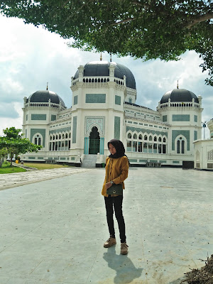  Masjid Raya AL- Mashun Medan Tempat wisata Religi yang kini berusia 113  Tahun  Medan seperti tak ada habisnya untuk ditelusuri, kamu yang suka wisata sejarah atau heritage seperti Saya pasti tak akan melewatkan tempat yang satu ini, yah Masjid Raya Al- Mashun Medan meninggalkan banyak sejarah di dalamnya. Masjid yang berlokasi tak jauh dari pusat kota Medan ini terletak di Jalan Sisingamangaraja No.61Medan Maimun. Pembangunan Masjid Al- Mashun sendiri dimulai pada tanggal 21 Agustus 1906 (1 Rajab 1324 H) oleh Sultan Ma’mun Al- Rasyid Perkasa Alam yakni pemimpin Kesultanan Deli pada masa itu. Dan secara keseluruhan pembangunan selesai pada tanggal 10 september 1909 yang artinya waktu pembangunan yang dibutuhkan adalah 3 tahun lebih. Dilansir dari Simas.kemenag.go.id Masjid yang Luas bangunannya sampai 5.000 m2 menelan biaya pembangunan mencapai satu juta Gulden. Kemudian Masjid ini juga ini memiliki daya tampung hingga 1.500 jamaah. Masjid yang dibangun di atas lahan seluas 18.000 kini sudah memasuki usia satu abad lebih, tepatnya berumur113 Tahun.  Menurut sejarahnya, Sultan Ma’mun Al-Rasyid memang sengaja membangun Masjid ini dengan megah, karena menurut prinsip nya hal itu lebih utama ketimbang kemegahan Istananya sendiri, yakni Istana Maimun yang berjarak 200m dari Masjid. Kemudian, pembangunan Masjid ini ditanggung sendiri oleh Sultan Ma’mun Al- Rasyid, namun konon katanya Tjong A Fie, tokoh saudagar kaya dari etnis Tionghoa ini pun turut berkontribusi dalam pendanaan pembangunan Masjid Raya ini. Pada mulanya arsitek yang merancang bangunan Masjid Raya ini merupakan Van Erp arsitek asal Belanda yang sebelumnya juga merancang Istana Maimun, namun kemudian prosesnya dikerjakan oleh JA Tingdeman. Alasanya karena ketika itu Van Erp dipanggil ke pulau Jawa oleh pemerintah Hindia Belanda untuk bergabung dalam proses restorasi candi Borobudur di Jawa Tengah. Kemudian JA Tingdeman merancang masjid ini dengan denah simetris segi delapan dalam corak bangunan campuran Maroko, Eropa dan Melayu serta Timur Tengah.  Pada bangunan masjid dibagi atas beberapa ruang utama, tempat wudhu, gerbang masuk dan menara. Ruang utama, tempat sholat berbentuk segi delapan tidak sama sisi. Pada sisi berhadapan lebih kecil, terdapat beranda yakni serambi kecil yang menempek menjorok keluar. Di bagian dalam masjid terdapat pilar utama berdiameter 0.60 m yang menjulang tinggi. Masjid Raya Al- Mashun didominasi warna putih, di samping hijau pada sekitar bagian pintu-pintu dan warna hitam pada kubahnya. Pilar-pilar yang terdapat pada setiap sisi bangunan untama mengambil corak khas Cordoba dan spanyol, terutama dengan lekung bagian atas yang berbentuk setengah lingkaran. Untuk membangun Masjid Raya Al- Mashun banyak dekorasi yang diimpor dari mancanegara seperti marmer dari Italia, kaca patri asal Cina, dan lampu gantung dari Prancis. Seriap ornamen dihiasi dengan ukiran-ukiran indah bermatif floral atau geometris. Keindahan Masjid Raya Al-Mashun dan Istana Maimun menandakan tingginya peradaban Kesultanan Deli, sebagai suatu kedaulatan etnis Melayu yang sempat berjaya pada zaman lampau. 