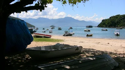 Playa tranquila sin olas con varios botes de pescadores fondeados