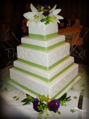 Elegant multitiered white square wedding cake with green ribbon trimming 