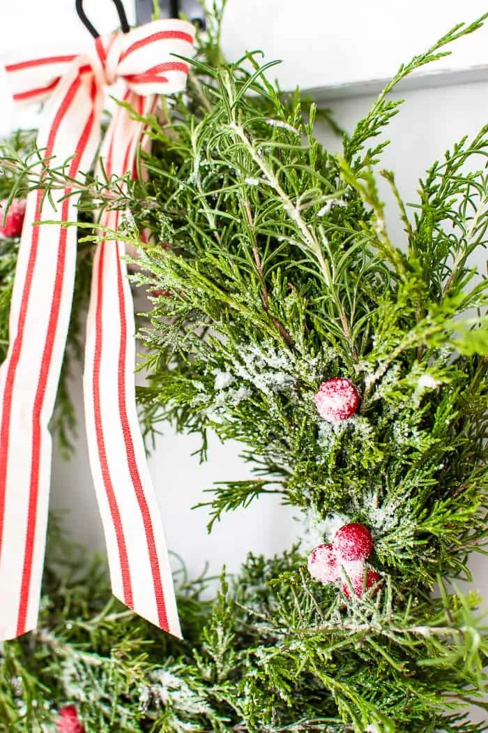 frosted cranberries on cedar rosemary wreath with red and white striped bow