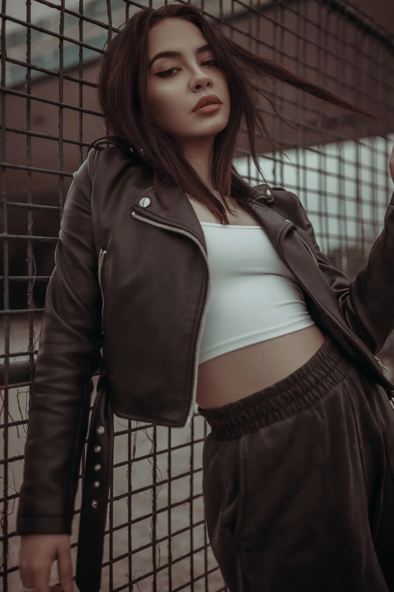 a beautiful, young woman with stylish haircut is wearing a stylish leather jacket and poses for the camera