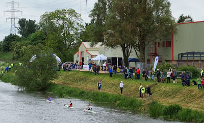 Many spectators standing as they encourage kayak competitors on the New River Ancholme during a  Keyo Brigg Bomber Quadrathlon
