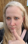 Photo of a woman with a neutral face showing a thumbs up