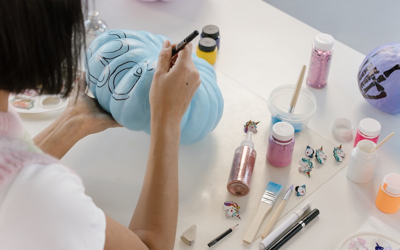 a woman painting a pumpkin for a contest