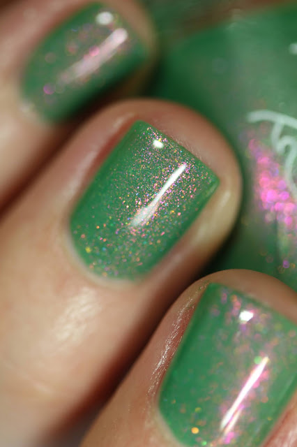 green nail polish with red and green shimmer swatched on white person's nails