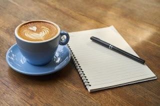 cup of coffee and jotter with pen on table for improving writing style