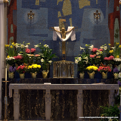 High Alter decorated for Easter with modern crucifix hanging above.