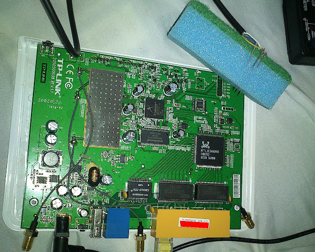 Internals of wifi router, serial needles poked through a sponge