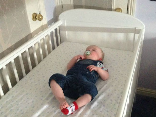 Baby asleep in cot lying on their back