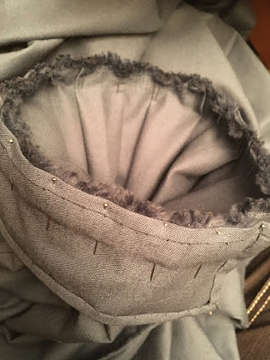 The cuff of a pair of blue pants, with thick, neatly pinned folds of fabric lining the inside and the fuzzy selvedges making a dense edge.