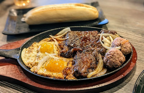 Bò né (beef steak with eggs and pork meatballs)