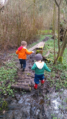 two toddlers playing outside in the woods