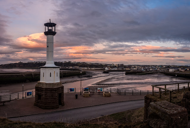 Photo of Maryport lighthouse at sunset with the town in the distance