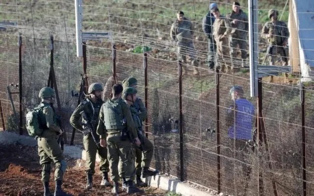 Membros da Força Interina das Nações Unidas no Líbano conversam com soldados israelenses através da cerca da fronteira nos arredores da vila de Kfarkila, no sul do Líbano | Jalaa Marey/AFP
