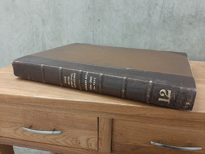 Colour photograph of a brown leather-bound volume sitting on a wooden table. The spine of the volume includes gold lettering stating it is the register of Archbishop Neville. The bottom of the spine includes a large gold-coloured number 12, reflecting the register number.