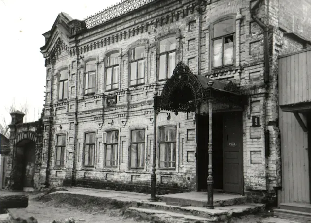 Старая фотография кирпичного здания с ажурным металлическим козырьком