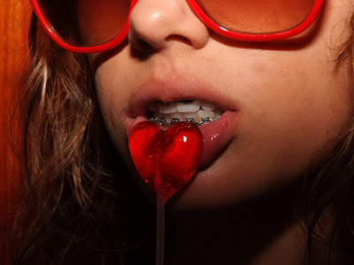 sexy young teen poses with some candy on her lips while baring her sexy braces.