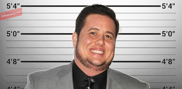 Chaz Bono standing in front of a height chart