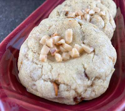 Cookies with cinnamon chips and toffe bits, topped with additional toffee bits. Photegraphed on a burgundy oblong plate