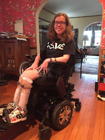 Kathleen sitting in her wheelchair wearing a 3E Love shirt that says "Love" with a "wheelchair heart" as the O