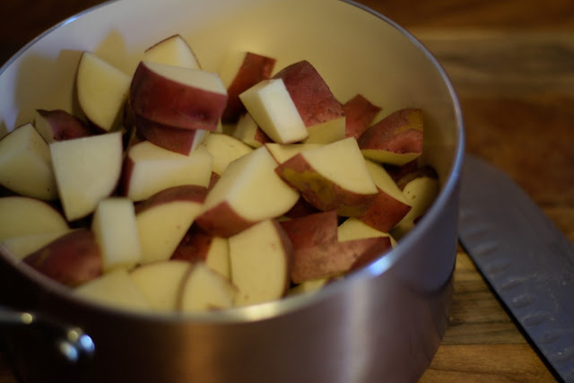 The diced red potatoes in a pot with a knife to the right of it. 