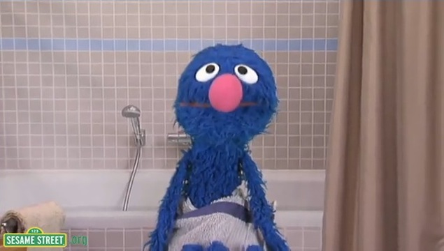 Grover wrapped in a towel standing in front of a bathtub