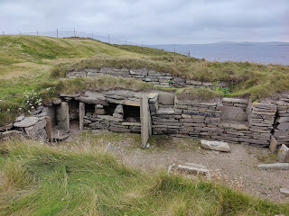 Knap of Hower, stone based building remains with no roof, showing storage areas and stones.