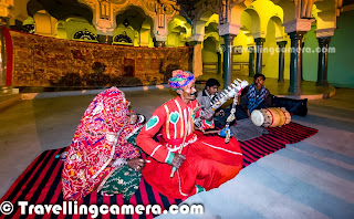 One of the exciting activity during our Churu trip was the beautiful evening when a bhopa family narrated the story of Pabuji, the Rathor Rajput Chief through their local musical instruments and songs describing the story. It was our last evening at Churu and next day we had to drive back to Delhi. The evening was full of fun with some of the awesome folk songs along with the popular lyrics like - 'Kesariya'. This Photo Journey shares some of the moments spent listening to 'Pabuji ki Phad' and dance moments with the family, who were telling this story.Deepak the owner of Malji Ka Kamara gave us some background about Pabuji Ki Phad - From where it started, who tell this story, what all instruments they use and various other things as the evening progressed.'Pabuji Ki Phad' is a basically a religious painting, which is mainly used for telling a musical story of Pabuji. Pabuji is considered as the Rathod Rajput chief. Bhopas of Pabusar are considered as traditional narrators of this art form. This art of telling story of Pabuji is very popular in Indian state of Rajasthan and it seems that there are very few folks in the world who know about this story. and there are only handful of folks, who know the complete story of Pabuji. Pabuji is also known as 'the Ascetic Deity of Sand Desert'. More about 'Pabuji Ki Phad' can be checked at - http://en.wikipedia.org/wiki/Pabuji_Ki_PhadThis family came dressed in red with all their musical instruments including a Ravan-hattha; which is made up of goat skin and camel teeth, a dhol and a metallic instrument. The man in left photograph was the leader, who was singing with Ravan-hattha and his wife was singing along at relevant places. One of his cousins was on dhol and son was dancing of the songs.Many times the lead musician stood up to accompany his son in dancing on beautiful rajasthani folk songs. It was awesome to see him dancing along with singing and playing ravan hattha.It is believed that Ravanhatha is originated among the Hela civilisation of Sri Lanka in the time of King Ravana. The bowl is made of cut coconut shell, the mouth of which is covered with goat hide. The stick is made up of bamboo, which is attached to this shell. There are two main strings - one is made up of steel and the other is made up of a set of horse hair. To know more about Ravanhatha, check out - http://en.wikipedia.org/wiki/Ravanahatha .Not sure, how many of us could really appreciate the epic of Pabuji but for sure, everyone of us enjoyed a lot on the music showcased by this family. Almost everyone of us danced with them on floor and few of the girls made best use of this opportunity to try out all the steps used by the Rajasthani  folks at Malji Ka Kamara. Overall experience was great and thanks for Mr. Lalji who corrected many of the facts which were being presented to us during the story telling part. Usually it's difficult to complete this story in an evening and it's not even recommended. But it's a good way for making people aware about these folk arts which are there for so many years and it's good to see that some of these folks are keeping it alive. The Churu ended very well with this performance by folks of Rajasthan, India.We shall go to Churu to experience this better !