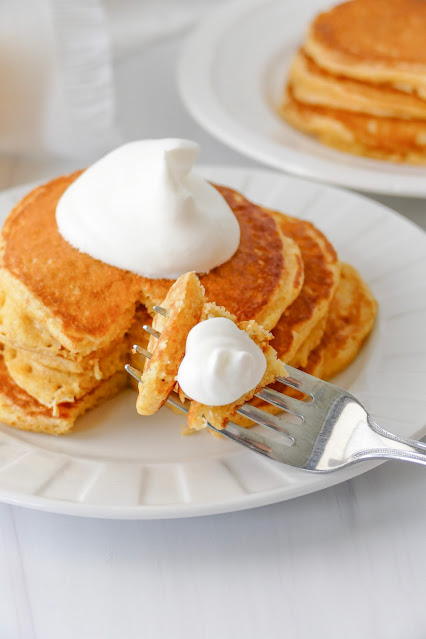 fork with a pancake bite sitting on the plate with the pancake stack.