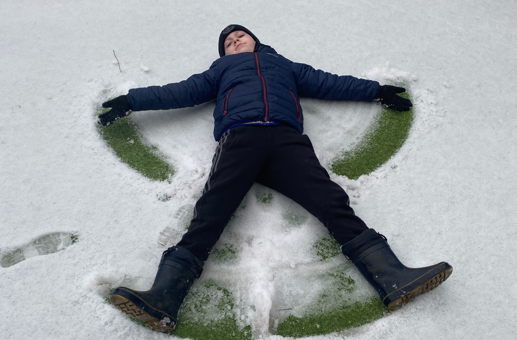 a boy making a snow angel in the snow