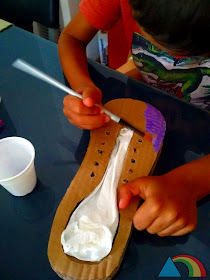 Niño pintando un zapato hecho con cartón