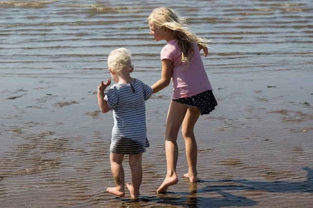 Sisters holding hands and heading into the sea