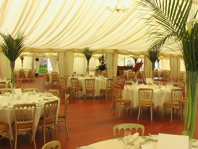simple-garden-wedding-party-under-giant-white-tent-round-dining-table-with-white-table-cloth-palm-leaf-table-centerpiece-laminate-flooring-traditional-wedding-decor