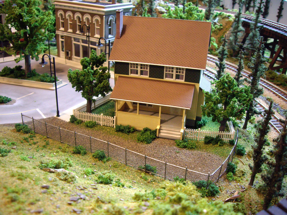 Kate’s Colonial Home kit with surrounding scenery including trees and a chain link fence