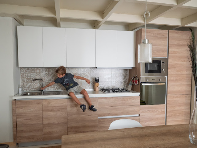 Niño sentado en la encimera de la cocina en blanco y madera clarita