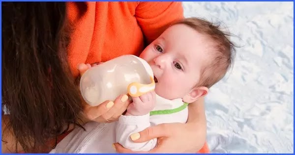 Bebé tomando leche en biberón. Niño.