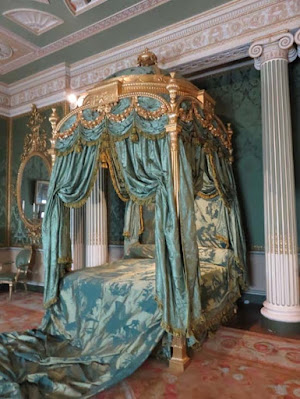 four poster bed with dome and bedspread running off of it