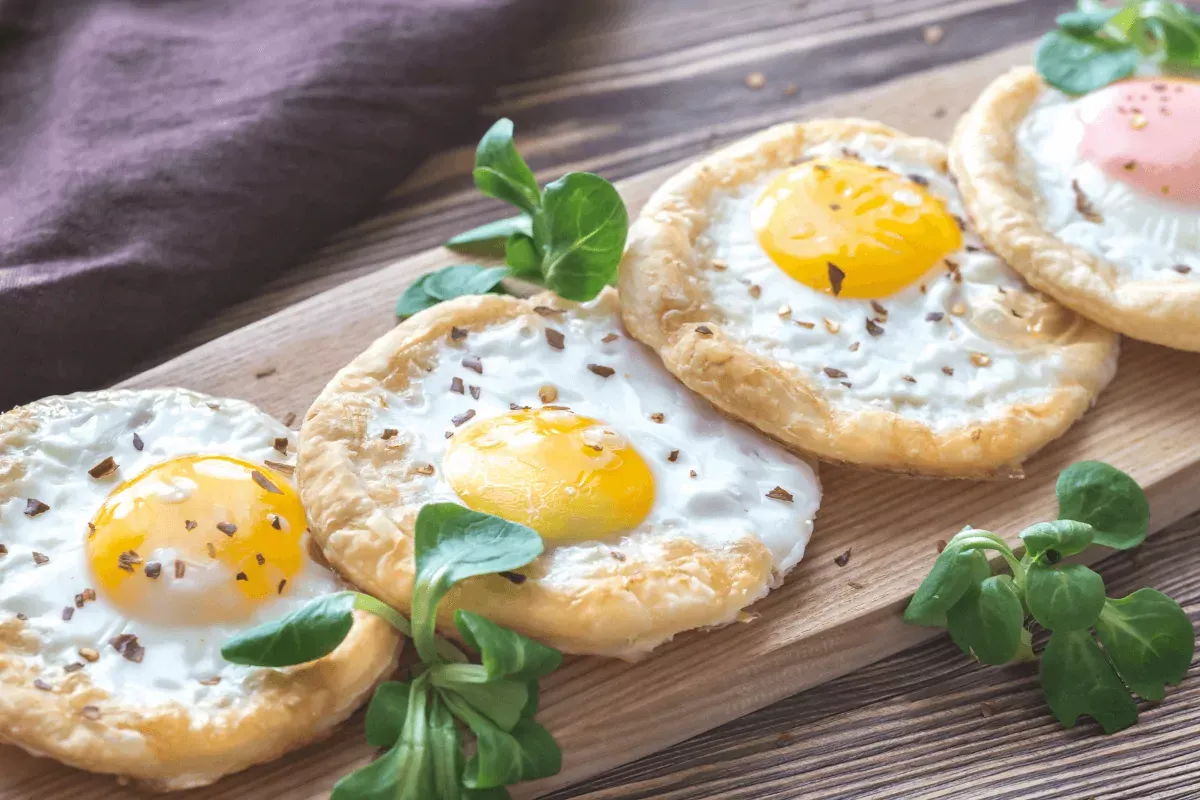 Baked eggs in puff pastry on the wooden board