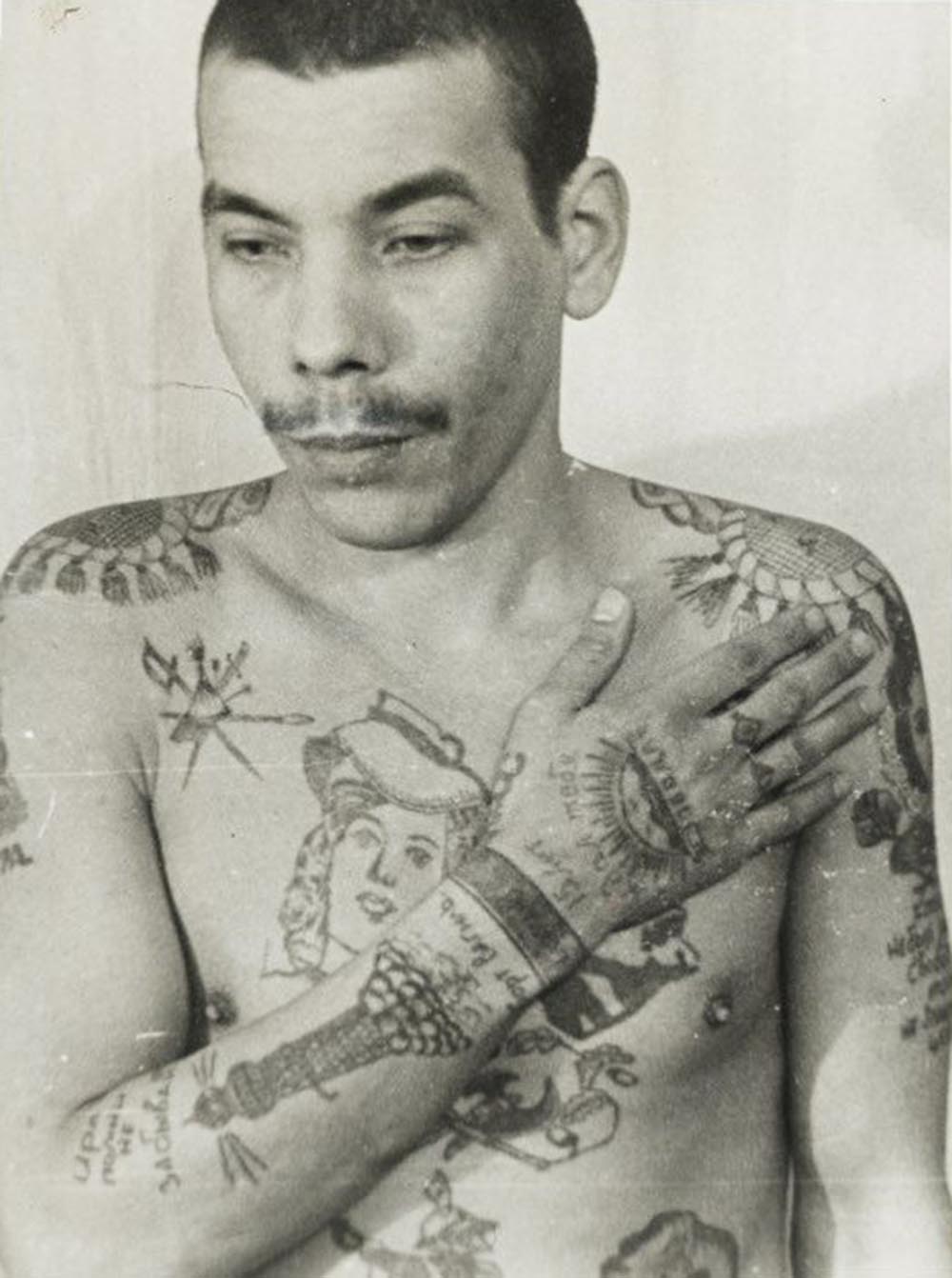 This man is a Muslim; his features also indicate he is not Russian. Text on the arm reads 'Remember me, don't forget me' and 'I waited 15 years for you.' On his stomach (left) is a religious building with a crescent moon. He is not an authoritative thief, but has tried to imitate them with his tattoos to increase his standing within the prison. The lighthouse on his right arm denotes a pursuit of freedom. Each wrist manacle indicates a sentence of more than five years in prison.