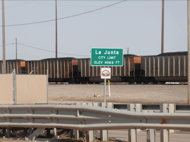 city limit sign in front of train cars loaded with coal
