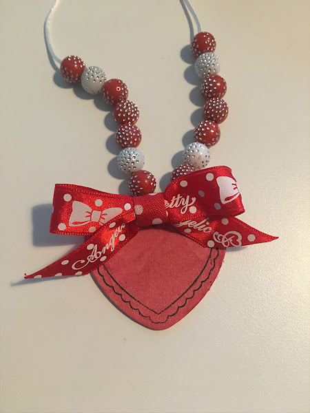 red beads on a string with a heart shaped pendant