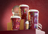 A selection of cylindrical tall red cups with costa coffee in white font with drawings of animals and snow covered square windows with white circular lids on a bright background