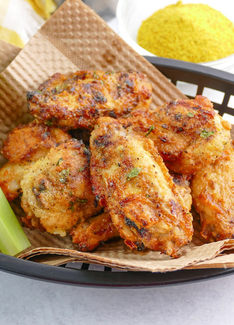 wings stacked in a black basket with brown paper liner.