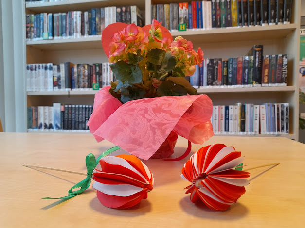 Zdjęcie prac uczniów i kwiatów na tle książek