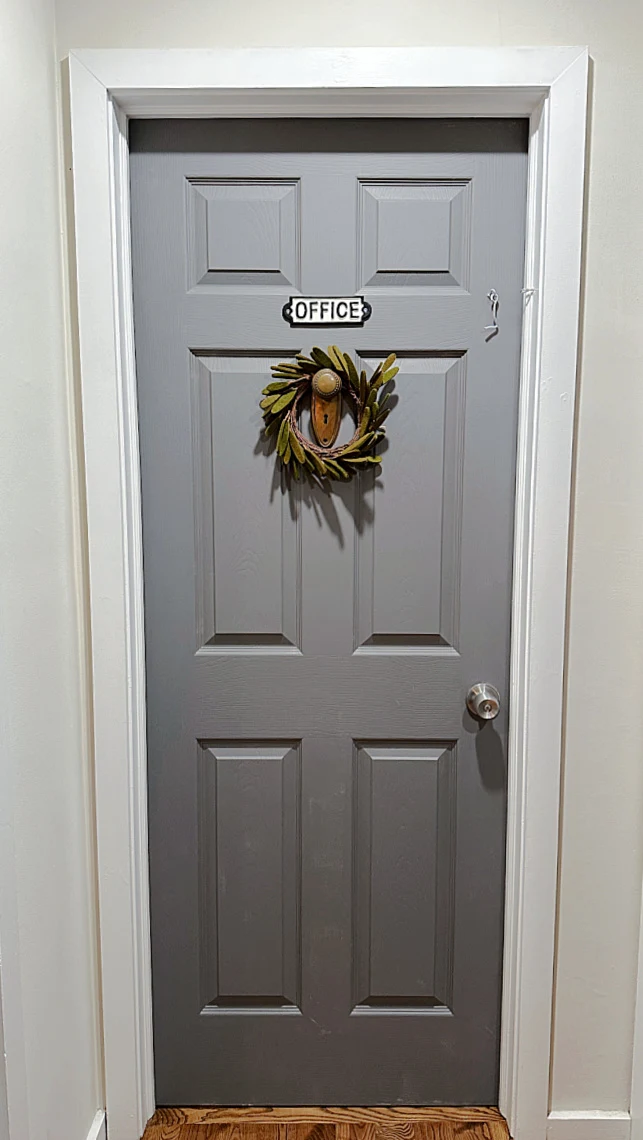 grey door with wreath and sign